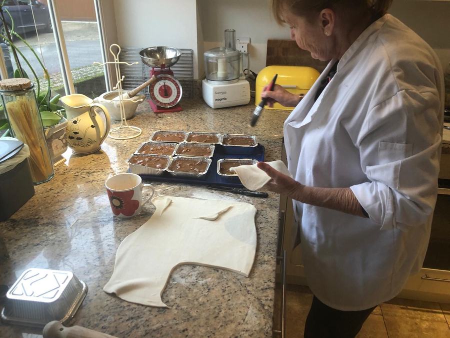 A member of the catering team preparing desserts on a kitchen counter.
