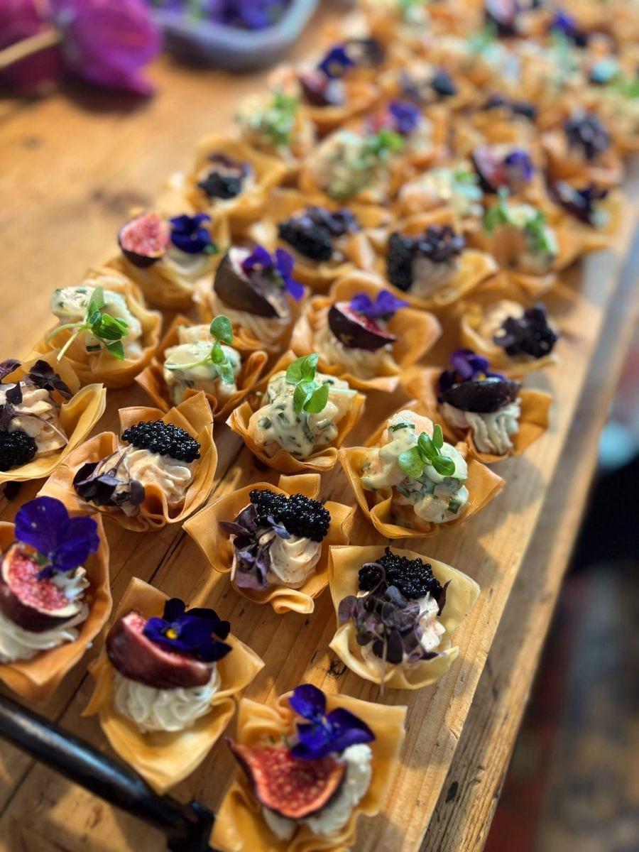 A tray of filo canapes with edible flowers, shot close up.